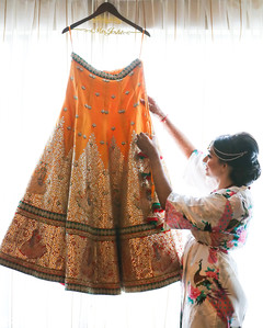 Lovely bride admiring her orange lengha set with golden details. Lovely bride admiring her orange lengha set with golden details.