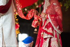Sikh bride follows the groom holding on to her end of the palaa. Sikh bride follows the groom holding on to her end of the palaa.