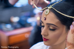 Indian bride putting on her hair jewelry. Indian bride putting on her hair jewelry.