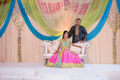 Charming indian couple posing at a colorful sangeet stage. Charming indian couple posing at a colorful sangeet stage.