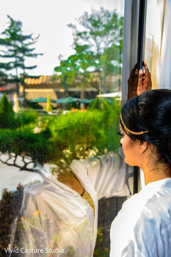 Indian bride taking a look outside while getting ready. Indian bride taking a look outside while getting ready.